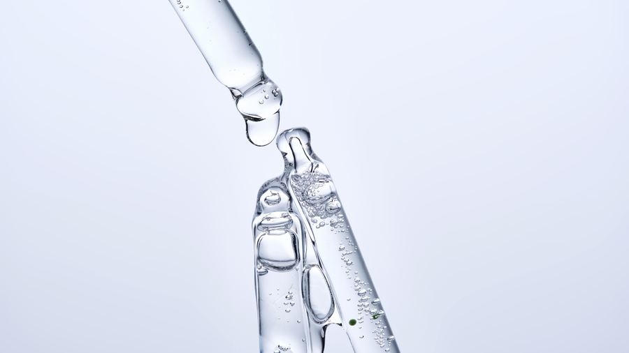 Clear glycerin serum dripping from a glass dropper