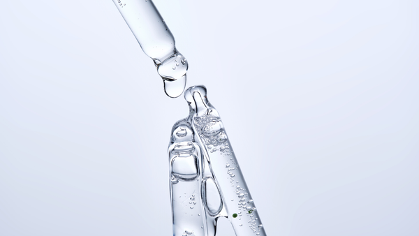 Clear glycerin serum dripping from a glass dropper