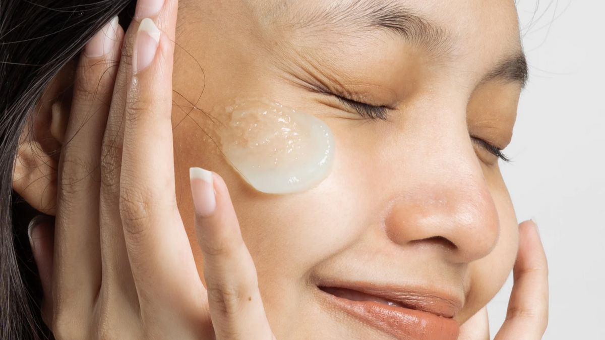 Woman applying moisturizer gel to facial skin